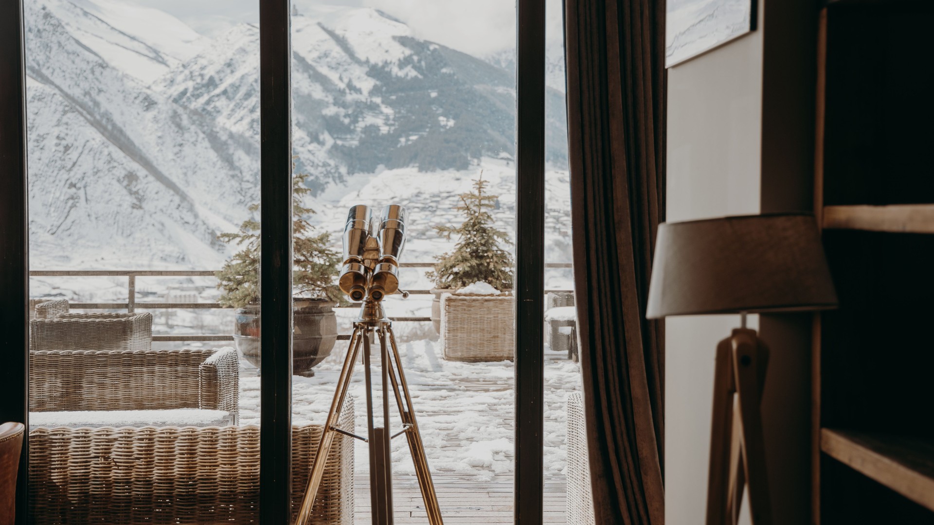 Warm mountain interior with large windows overlooking naturally snow-covered mountains — illustrative image